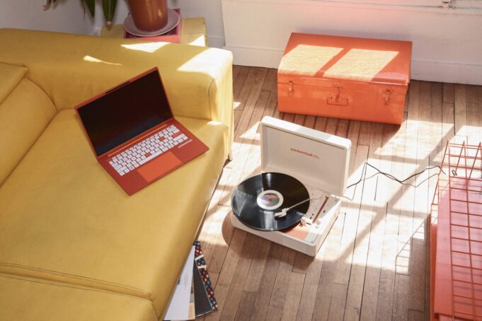 Orange Packard Bell DotBook laptop on a yellow sofa beside the DotLoop suitcase turntable