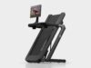 Peloton Tread Flex folded upright on a pale studio floor with a swivel screen showing a strength class