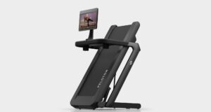 Peloton Tread Flex folded upright on a pale studio floor with a swivel screen showing a strength class