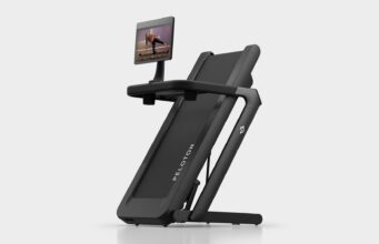 Peloton Tread Flex folded upright on a pale studio floor with a swivel screen showing a strength class