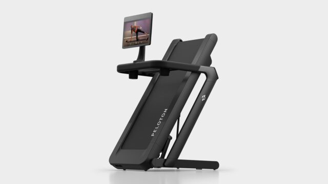 peloton-tread-flex-folded Peloton Tread Flex folded upright on a pale studio floor with a swivel screen showing a strength class