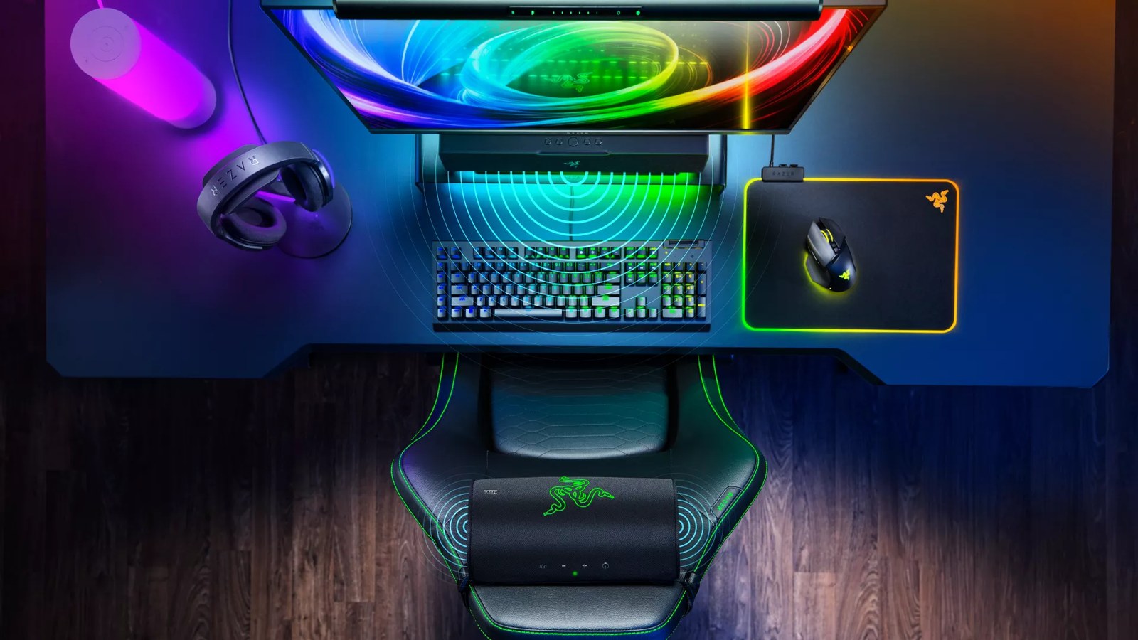 Top-down view of a Razer desk setup showing the Razer Clio X on the chair as a rear speaker behind a soundbar