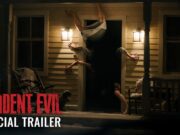 A figure contorted upside down in the doorway of a lit farmhouse porch at night, from Sony's Resident Evil official trailer