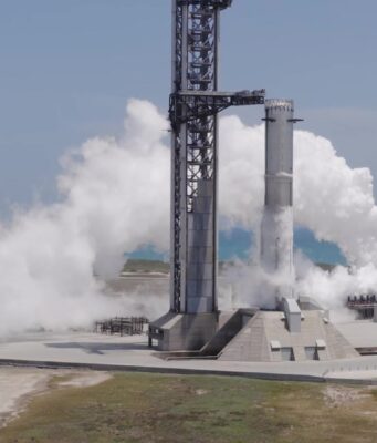 Starship Flight 14 Targets September 28 for SpaceX’s First Trip to Orbit A SpaceX Super Heavy booster on the launch mount beside the launch tower at Starbase, wrapped in white vapor with the Gulf behind it