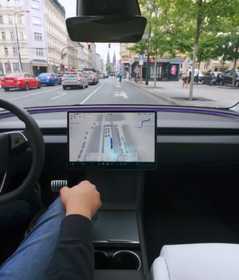 Tesla cabin with a visualization map on the center screen while the car drives through a European city street