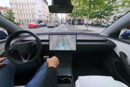 Tesla cabin with a visualization map on the center screen while the car drives through a European city street