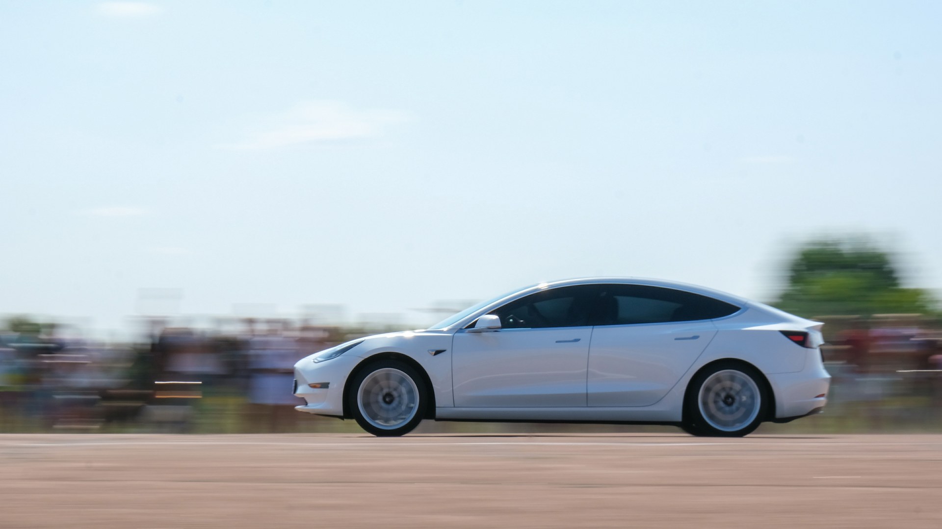 White Tesla Model 3 sedan in profile on a paved test stretch