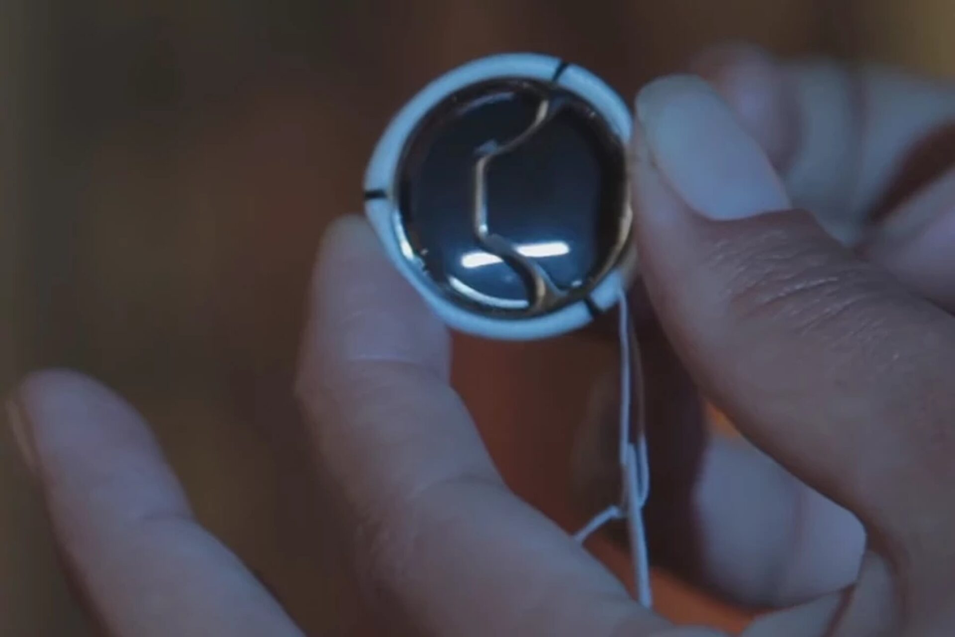 AUTUS valve held between fingers, showing its opening and frame