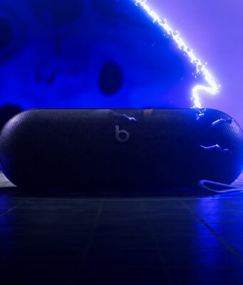 Beats Pokémon Pill Teaser Leaves Price and Date Unconfirmed AI-relit illustration of the Beats Pokémon Pill teaser, showing the speaker and strap against blue electrical effects