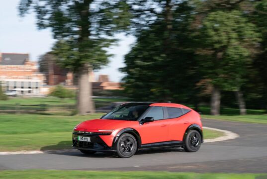 Red Hyundai IONIQ 3 electric hatchback driving on a UK road