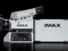An IMAX film camera and its film magazine, photographed on a black background