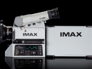 An IMAX film camera and its film magazine, photographed on a black background