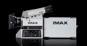 An IMAX film camera and its film magazine, photographed on a black background