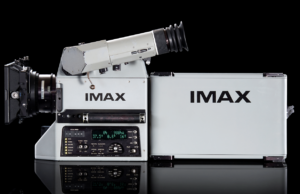 An IMAX film camera and its film magazine, photographed on a black background