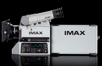An IMAX film camera and its film magazine, photographed on a black background