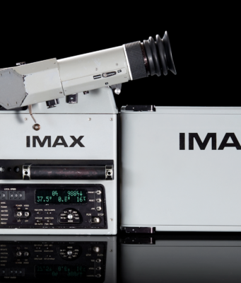 An IMAX film camera and its film magazine, photographed on a black background