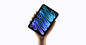 Apple’s New iPad mini Gets an OLED Display and A20 Pro Chip A hand holding the new midnight iPad mini, its OLED display showing blue and purple mini lettering against a black background