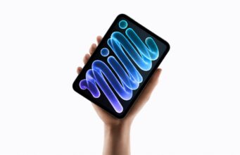 Apple’s New iPad mini Gets an OLED Display and A20 Pro Chip A hand holding the new midnight iPad mini, its OLED display showing blue and purple mini lettering against a black background