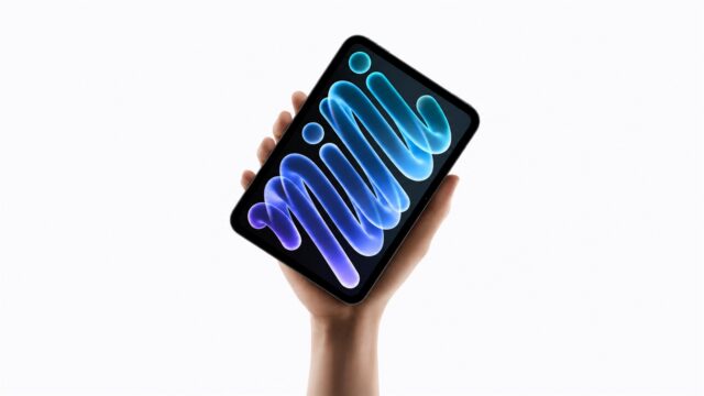 ipad-mini-oled-a20-pro-hero-1600x900-1 A hand holding the new midnight iPad mini, its OLED display showing blue and purple mini lettering against a black background