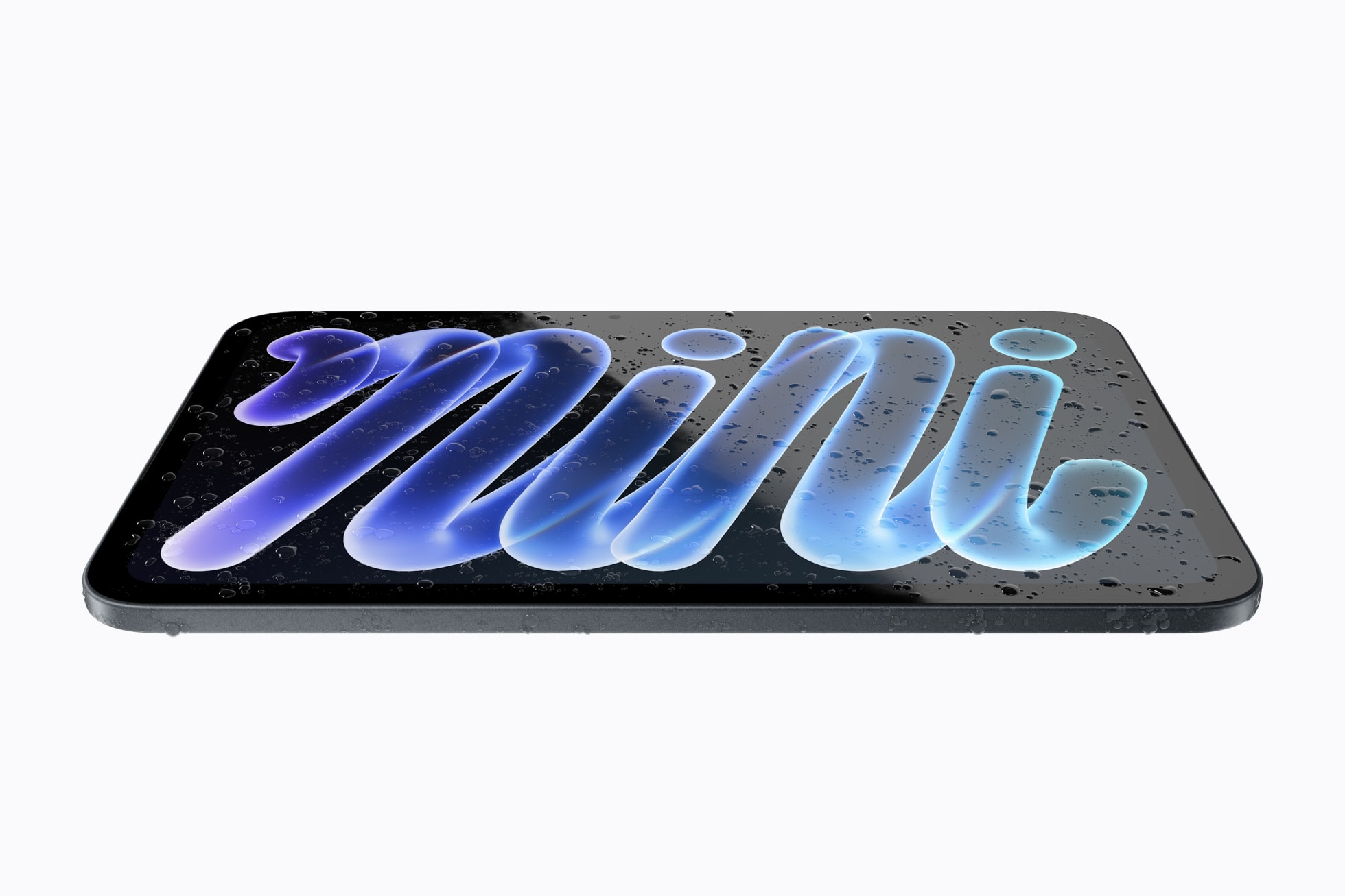 The new midnight iPad mini lying flat on a pale surface, its display showing blue and purple mini lettering under scattered water droplets