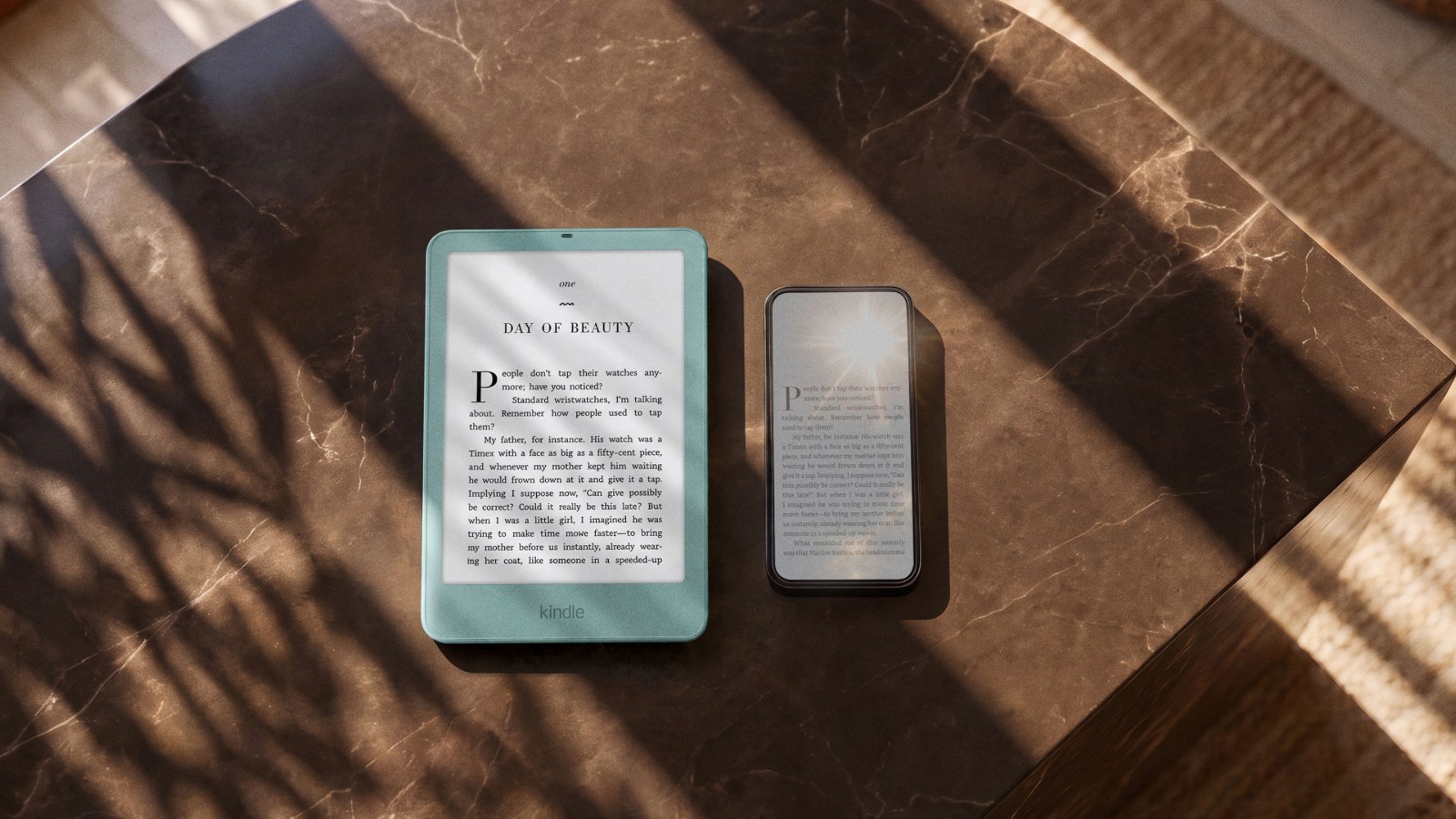 New Kindle Paperwhite in Seaglass Green lying next to a smartphone on a marble table in sunlight
