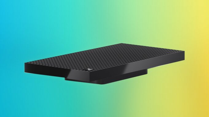 Surface RTX Spark Dev Box angled on a blue, purple and yellow gradient backdrop, showing the perforated top and the Microsoft logo