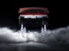 Rear view of the redesigned Tesla Roadster with its active wing deployed, four underbody suction fans, and cold-gas thrusters firing white plumes