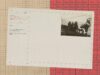 Vintage archival card with a photograph of workers aboard a ship replacing buoys, laid over a beige grid and a red table of numbers