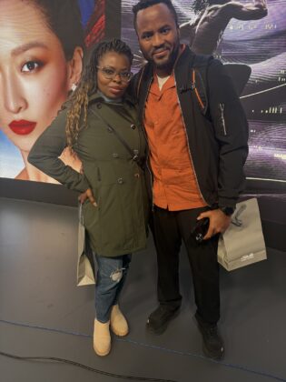 Two attendees pose beside the creative display wall at Pier59 Studios