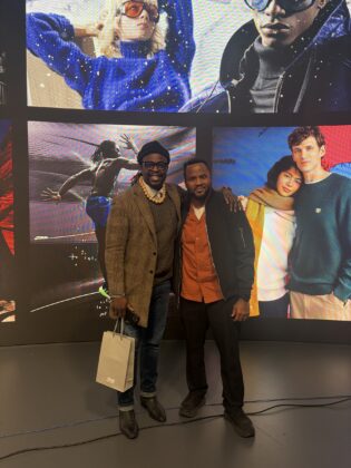 Three attendees pose in front of the creative display wall at Pier59 Studios