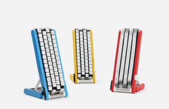 Google Japan’s Gboard Conveyor Belt Keyboard Brings the Keys to You Three conveyor-belt keyboards on stands in blue, yellow and red, each with white keycaps mounted on four vertical belts; the red unit's belts are blurred with the keys in motion