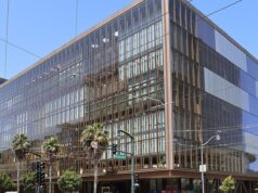Glass-fronted office building at 1515 Third Street in San Francisco's Mission Bay, with palm trees and a traffic signal at the corner