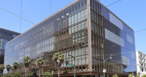 OpenAI Engineer Charged Over Hidden Recording Device in Executive Room Glass-fronted office building at 1515 Third Street in San Francisco's Mission Bay, with palm trees and a traffic signal at the corner