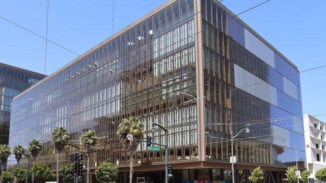 Glass-fronted office building at 1515 Third Street in San Francisco's Mission Bay, with palm trees and a traffic signal at the corner