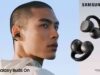 A person shown in profile wearing a black Galaxy Buds On clip-on earbud, beside two renders of the black open-ear earbuds