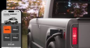 Slate Truck skips infotainment and waits on a later-year app Official Slate charging still: a phone Charge Summary screen showing 100 percent battery, 150 mi total range, 19 min charge time, 115 mi added, and $13.68 cost, beside a gray pickup with a plug in the rear charge port and a lit red tail lamp