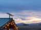 Starlink Residential vs Roam $55 monthly US plans use the same price for different service Starlink dish mounted on a green metal roof with string lights at dusk, fields and mountains behind it