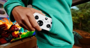 Xbox Nano Controller pre-order opens at $49.99 USD; prices vary A person in a teal hoodie pulls a white Xbox Nano Controller from a front pocket, with a television on in the background