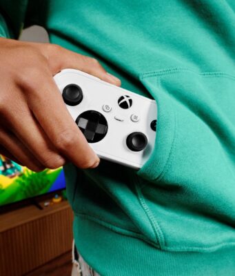 Xbox Nano Controller pre-order opens at $49.99 USD; prices vary A person in a teal hoodie pulls a white Xbox Nano Controller from a front pocket, with a television on in the background