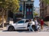 White Waymo Jaguar I-PACE robotaxi parked on a San Francisco street with riders loading the trunk
